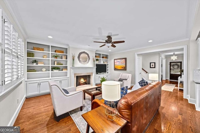 66 Mobile Ave NE, Atlanta, GA 30305 - living room featuring a warm lit fireplace, ornamental molding, light wood-style flooring, baseboards, and a ceiling fan