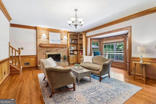 living area with crown molding, a chandelier, wainscoting, wood finished floors, and stairs
