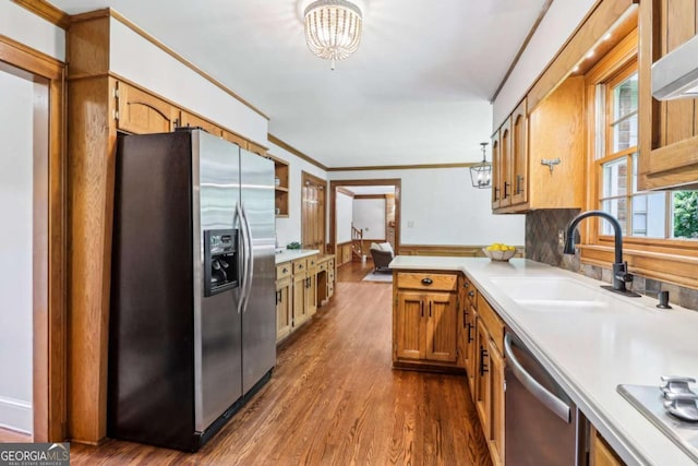 kitchen featuring stainless steel appliances, a sink, light countertops, dark wood-style flooring, and brown cabinetry