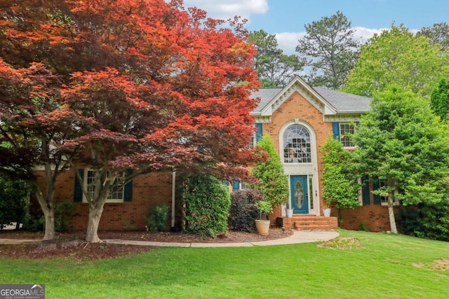 view of front of home featuring brick siding and a front lawn