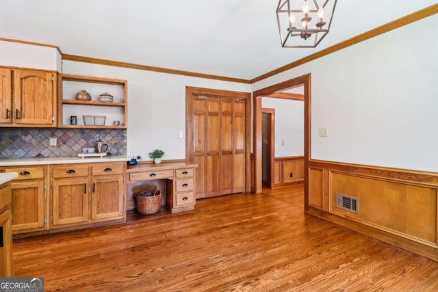 kitchen featuring light countertops, open shelves, a wainscoted wall, ornamental molding, and light wood finished floors