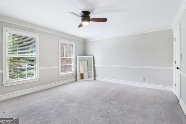 carpeted empty room featuring healthy amount of natural light, a ceiling fan, crown molding, and baseboards
