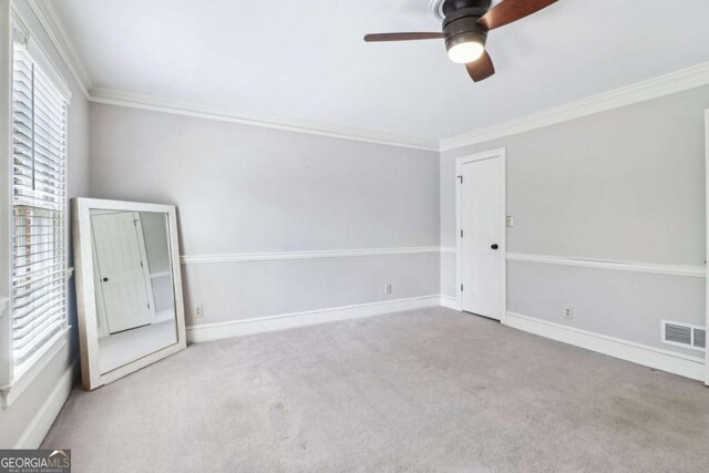 carpeted empty room with ceiling fan, crown molding, and baseboards