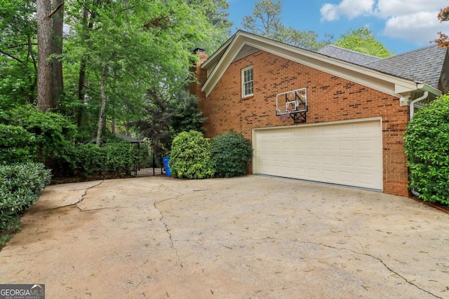 view of side of home featuring brick siding, a chimney, and driveway