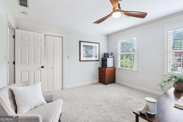 sitting room with healthy amount of natural light, a ceiling fan, baseboards, and crown molding