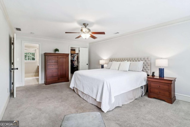 bedroom featuring ornamental molding, light colored carpet, a closet, a walk in closet, and baseboards