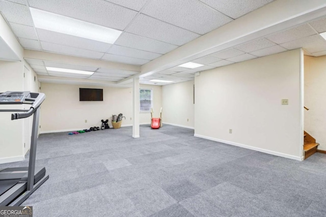 exercise room with a paneled ceiling, carpet, and baseboards