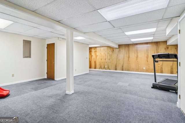 workout area with a drop ceiling, carpet, baseboards, and wood walls