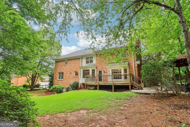 rear view of house featuring a wooden deck, a chimney, brick siding, and a lawn