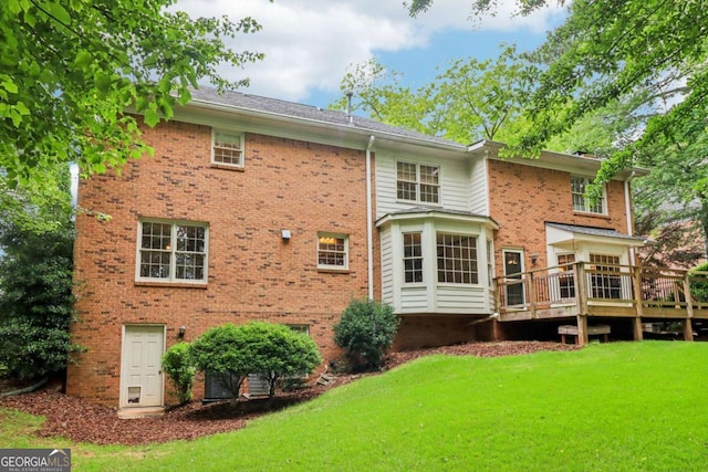 rear view of house with brick siding, a yard, and a wooden deck