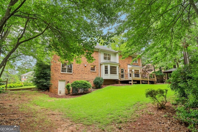 back of property featuring brick siding, a yard, and a deck