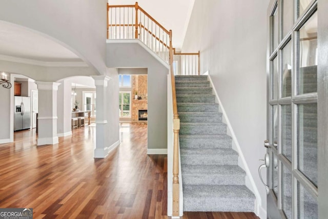 79 Gold Creek Ct, Dawsonville, GA 30534 - stairway with decorative columns, a high ceiling, arched walkways, wood finished floors, and a fireplace