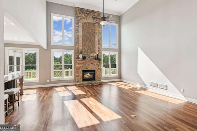 79 Gold Creek Ct, Dawsonville, GA 30534 - unfurnished living room with baseboards, wood finished floors, a stone fireplace, a towering ceiling, and crown molding