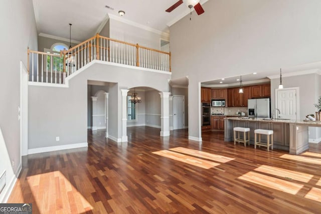 79 Gold Creek Ct, Dawsonville, GA 30534 - unfurnished living room featuring arched walkways, ceiling fan, a chandelier, dark wood-style floors, and ornamental molding
