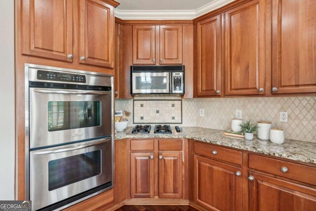 79 Gold Creek Ct, Dawsonville, GA 30534 - kitchen with stainless steel appliances, brown cabinets, light stone countertops, and decorative backsplash