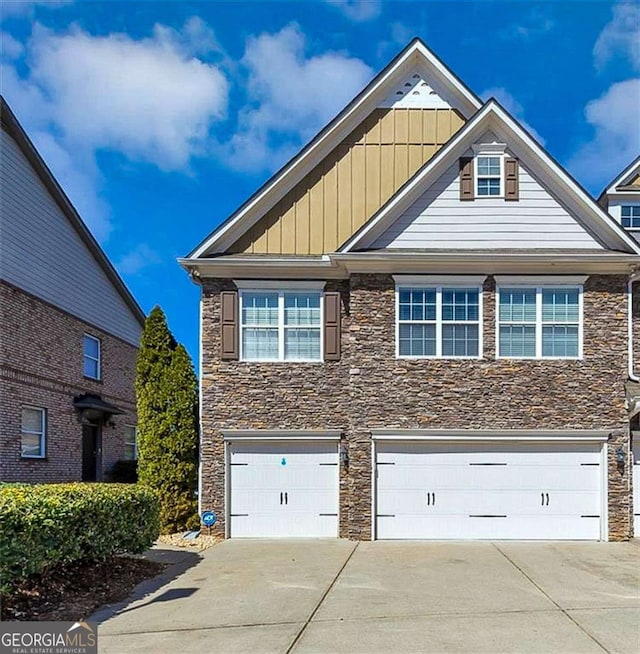805 Pleasant Hill Rd NW Unit 343, Lilburn, GA 30047 - view of front of home featuring stone siding, concrete driveway, an attached garage, and board and batten siding