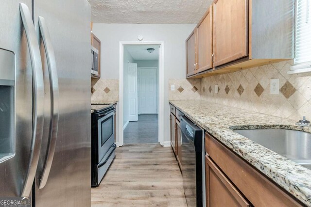 5509 Covent Way, Lithonia, GA 30058 - kitchen featuring stainless steel appliances, light wood-type flooring, light stone countertops, decorative backsplash, and a textured ceiling