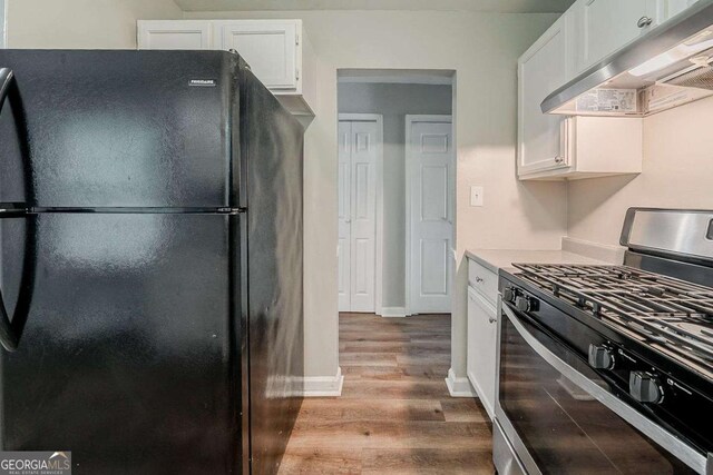 3731 Adkins Rd NW, Atlanta, GA 30331 - kitchen featuring freestanding refrigerator, stainless steel range with gas cooktop, under cabinet range hood, wood finished floors, and white cabinetry