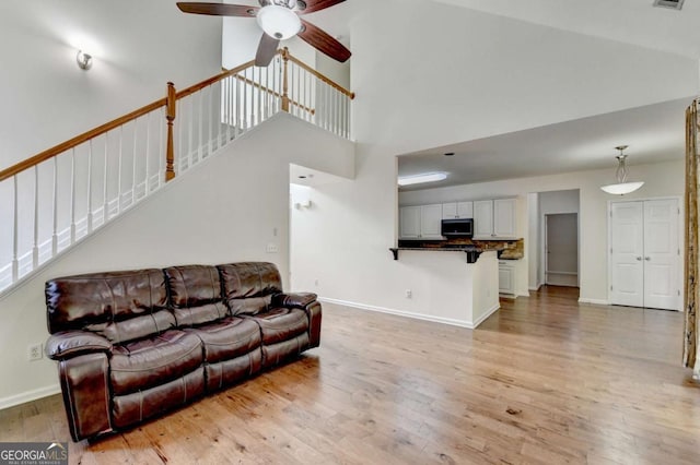 1095 S Bethany Creek Dr, Alpharetta, GA 30004 - living area featuring light wood finished floors, a ceiling fan, baseboards, stairs, and a towering ceiling