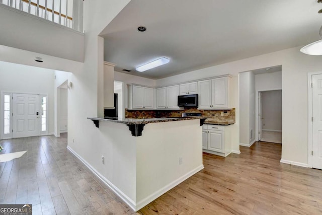 1095 S Bethany Creek Dr, Alpharetta, GA 30004 - kitchen with stainless steel microwave, light wood-style floors, decorative backsplash, and white cabinetry
