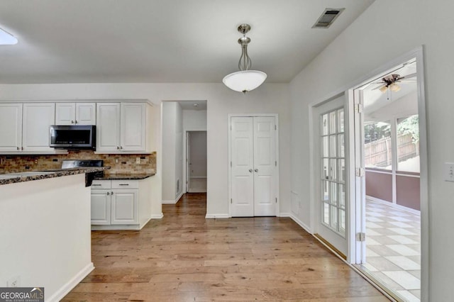 1095 S Bethany Creek Dr, Alpharetta, GA 30004 - kitchen with stainless steel microwave, white cabinets, light wood finished floors, decorative backsplash, and decorative light fixtures