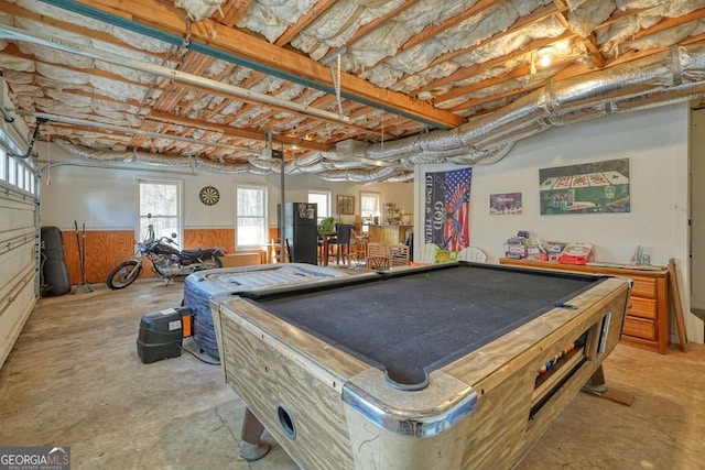 recreation room with unfinished concrete floors, a wainscoted wall, and billiards table