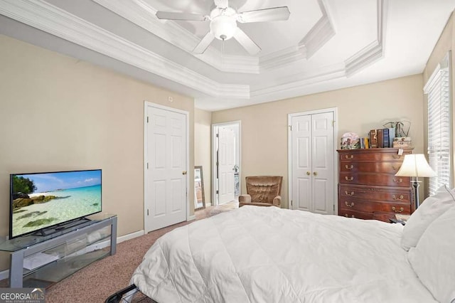 carpeted bedroom with crown molding, a tray ceiling, a ceiling fan, baseboards, and a closet