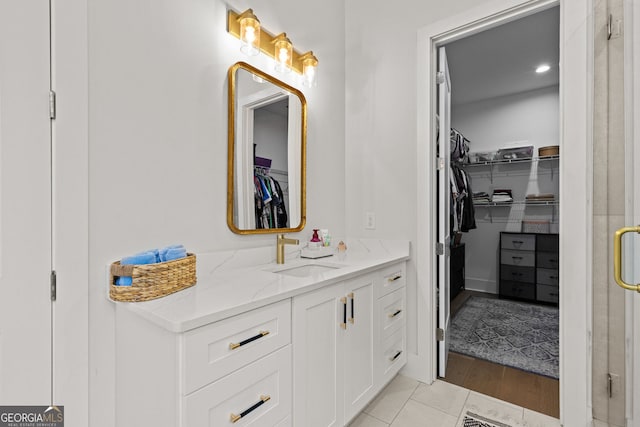 full bath with vanity, a stall shower, and a spacious closet