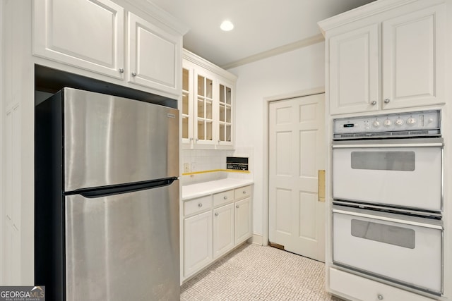 1256 Spring Park Dr SW, Atlanta, GA 30311 - kitchen featuring freestanding refrigerator, white double oven, decorative backsplash, glass insert cabinets, and light countertops