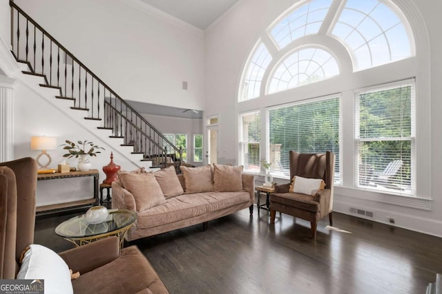 living room featuring wood finished floors, stairs, ornamental molding, a towering ceiling, and baseboards