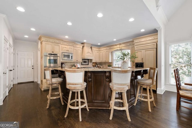 kitchen with stainless steel appliances, cream cabinets, premium range hood, crown molding, and baseboards