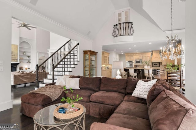 living room featuring ceiling fan, dark wood-type flooring, a chandelier, built in shelves, and stairs