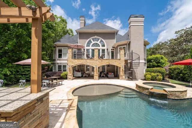 rear view of house featuring stairs, a balcony, a chimney, and a patio