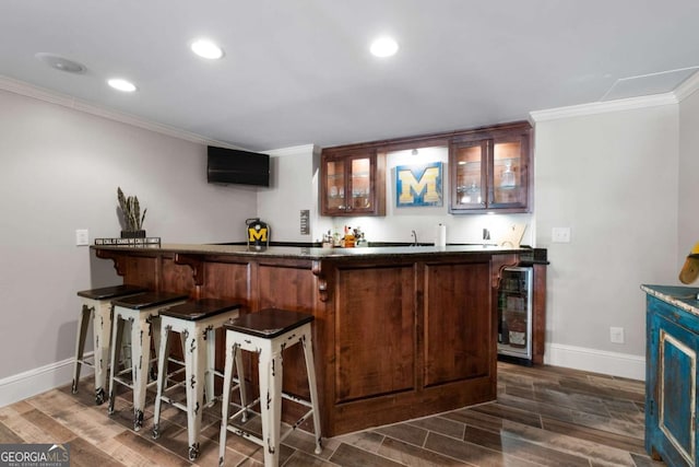indoor wet bar with baseboards, ornamental molding, beverage cooler, dark wood-style flooring, and recessed lighting