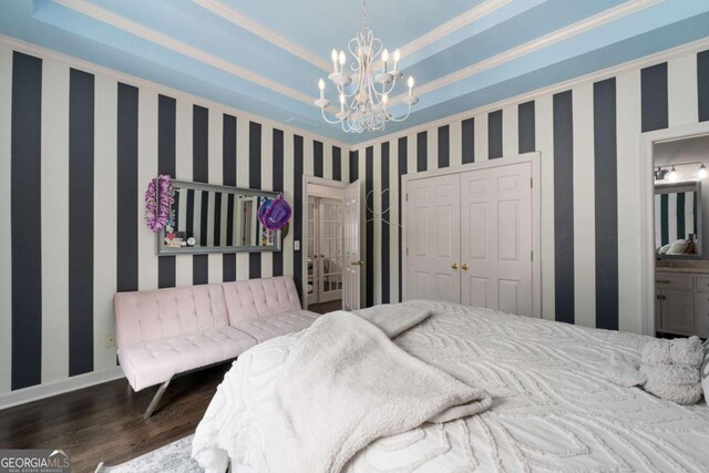 bedroom featuring wood finished floors, a closet, a chandelier, wallpapered walls, and ornamental molding