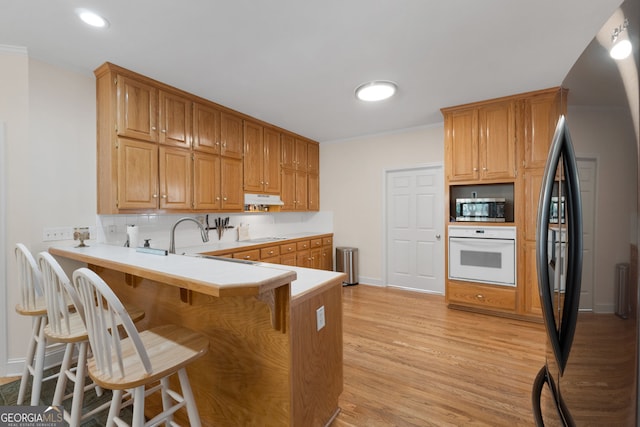 604 Clearwater Ct, Mcdonough, GA 30252 - kitchen with white appliances, under cabinet range hood, a peninsula, a breakfast bar area, and light countertops