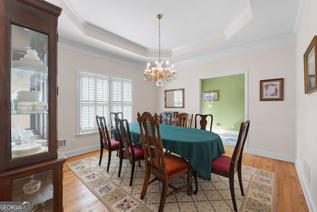 604 Clearwater Ct, Mcdonough, GA 30252 - dining area with a chandelier, light wood-type flooring, a tray ceiling, and crown molding
