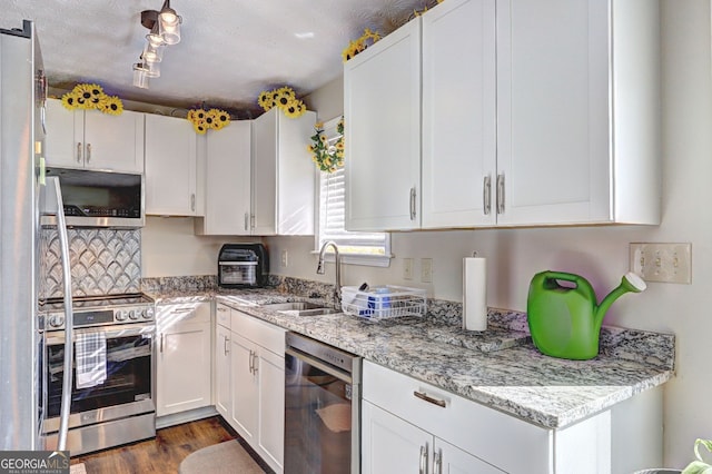 kitchen featuring appliances with stainless steel finishes, a sink, white cabinetry, and light stone countertops