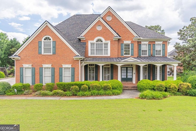 view of front of home featuring brick siding, a front lawn, a standing seam roof, and a porch