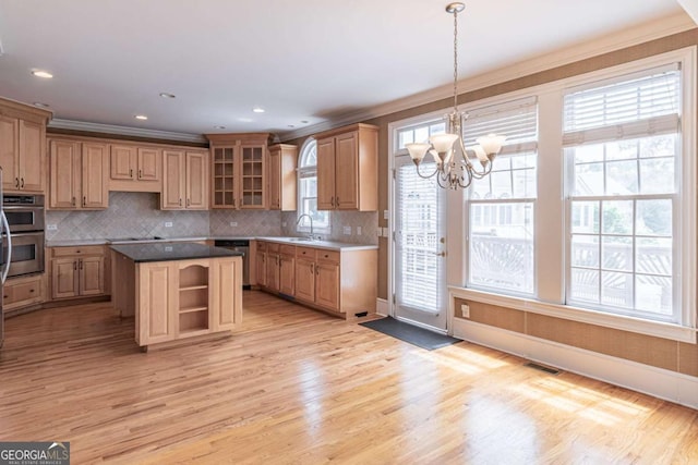 kitchen with a sink, appliances with stainless steel finishes, a chandelier, backsplash, and light wood-style floors