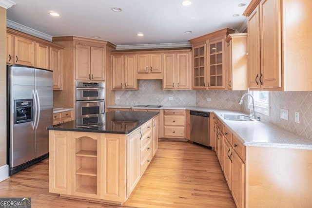 kitchen featuring stainless steel appliances, a sink, light brown cabinetry, light wood-type flooring, and a center island