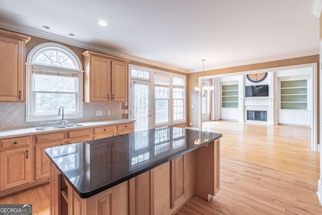 kitchen with a sink, crown molding, a chandelier, light wood-style floors, and a center island