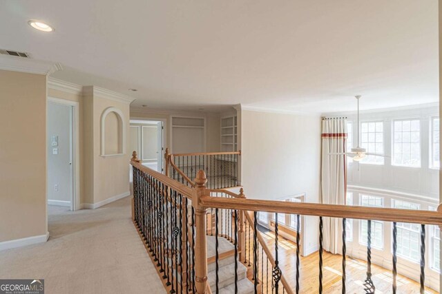 corridor with an upstairs landing, ornamental molding, baseboards, light colored carpet, and recessed lighting