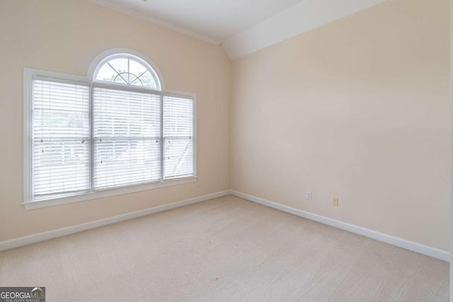 empty room featuring light carpet, baseboards, lofted ceiling, and ornamental molding