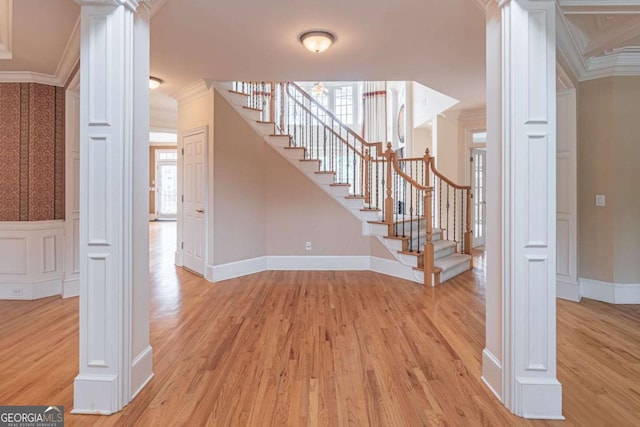 stairs featuring decorative columns, crown molding, wood finished floors, and baseboards