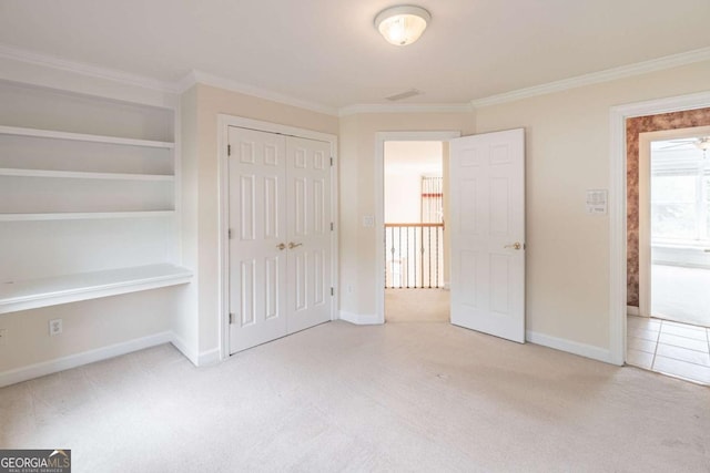 unfurnished bedroom with carpet flooring, crown molding, baseboards, and a closet