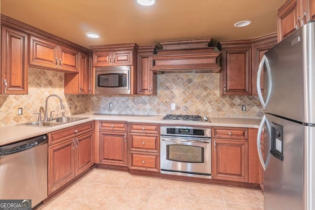 kitchen featuring appliances with stainless steel finishes, a sink, light countertops, and brown cabinets