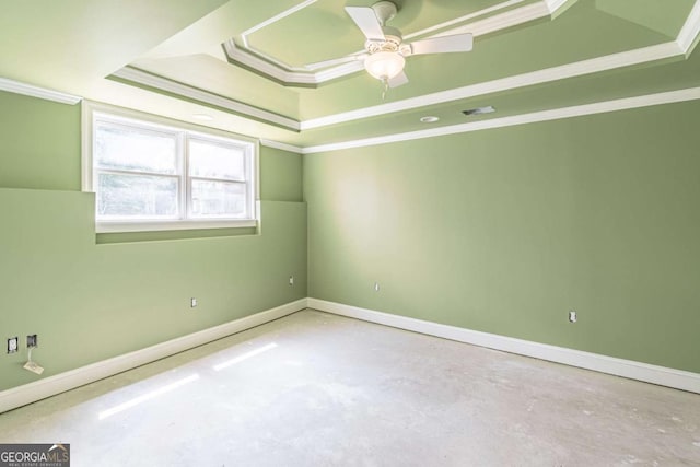unfurnished room with a raised ceiling, crown molding, unfinished concrete flooring, a ceiling fan, and baseboards