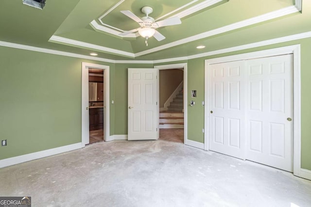 unfurnished bedroom featuring a raised ceiling, a closet, concrete floors, ensuite bathroom, and baseboards