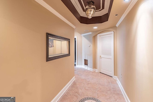 hallway with a raised ceiling, crown molding, baseboards, recessed lighting, and arched walkways